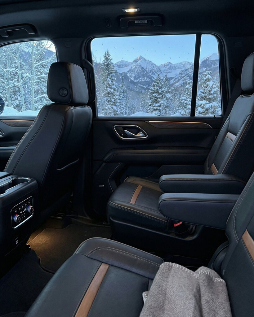 The interior of a luxury limousine with leather seats and a view of the Colorado mountains through the window.